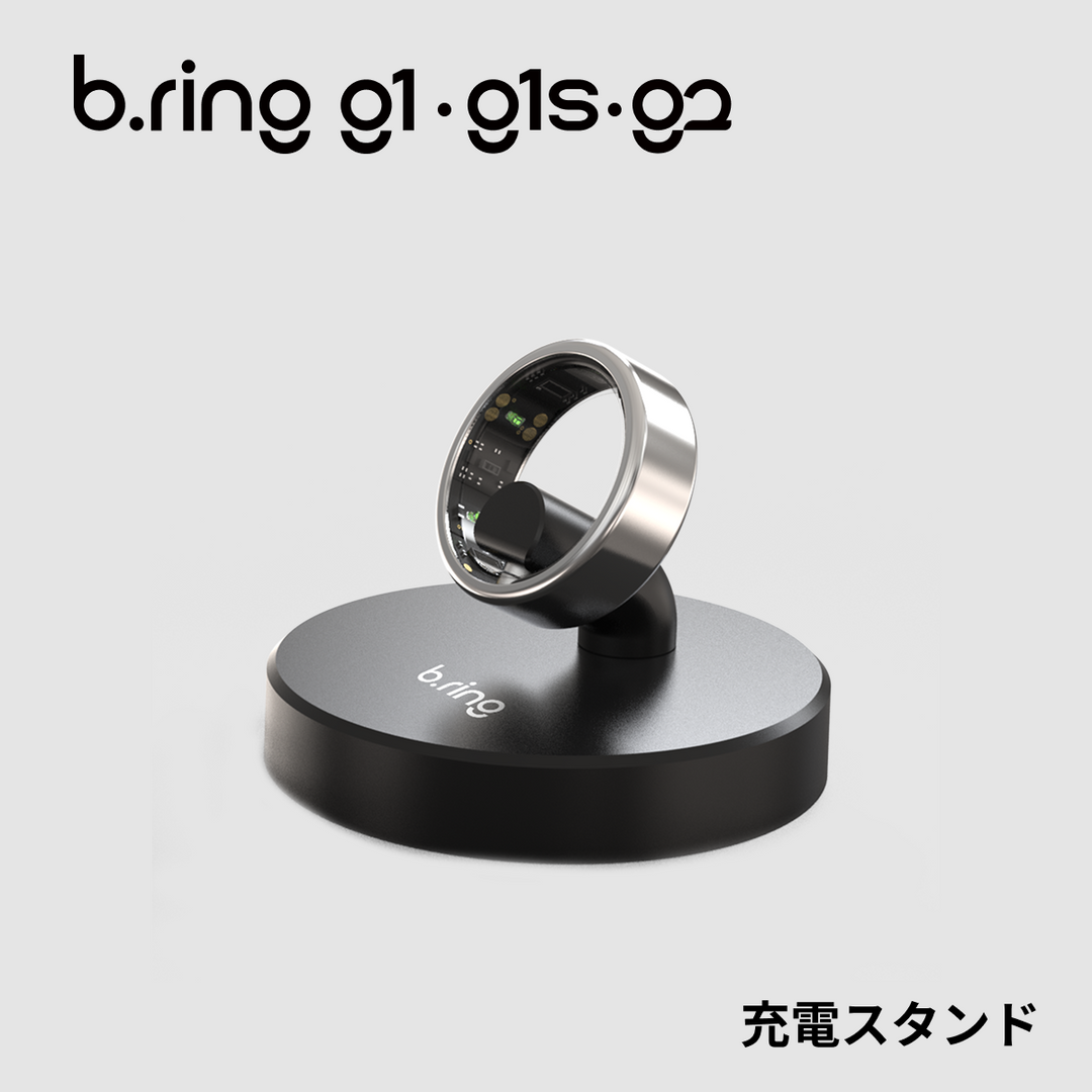 G1・G1S・G2共通対応の黒い円形充電スタンドにシルバーのb.ringスマートリングを立てて充電している商品画像